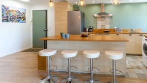 Une cuisine moderne dotée d’un îlot central, de tabourets de bar et de luminaires suspendus.