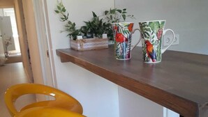 Eine Küche mit einer Holzarbeitsplatte, zwei gelben Barhocker und einer dekorativen Tasse mit Vogelmotiv.