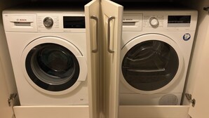 Un lave-linge Bosch à chargement frontal, situé dans une cuisine où se trouve également un four à micro-ondes au-dessus.
