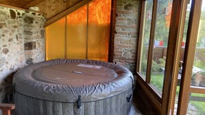 Un bain à remous dans une pièce rustique aux murs de pierre et aux poutres en bois.
