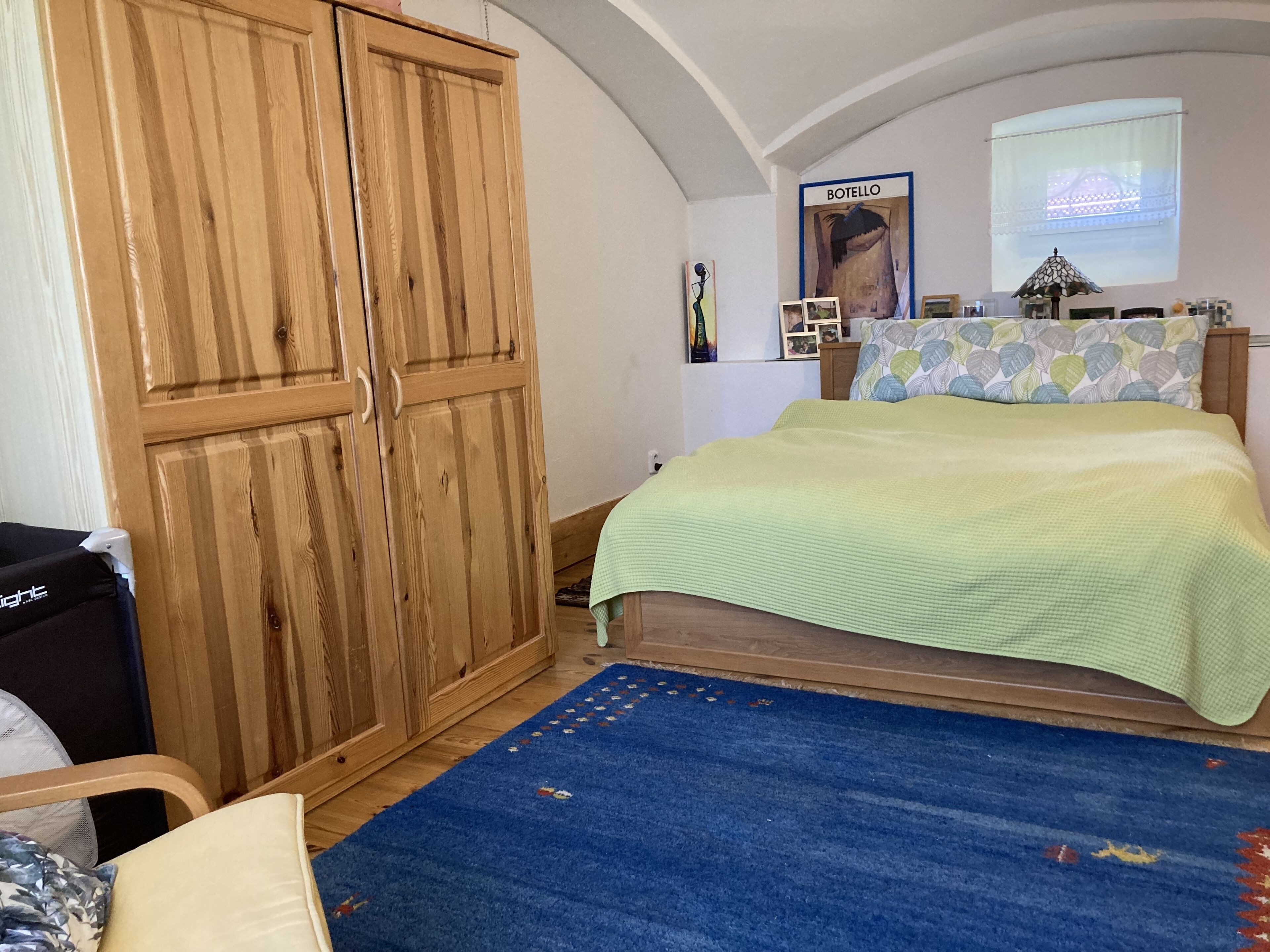 Un dormitorio con una cama, un tapete azul, un armario de madera y un cartel en la pared.