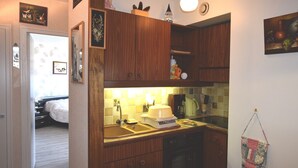 Una cocina compacta con armarios de madera, horno integrado y una pequeña encimera.