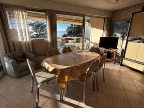 Ein Essbereich mit Tisch und Stühlen, einer Couch, einem Fernseher und Blick ins Freie.