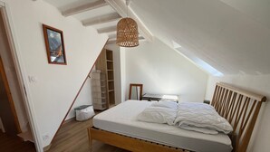 A bedroom with a wooden bed, a skylight, a wardrobe, and a hanging light fixture. - Charming house for 4 near town center (Sarzeau)