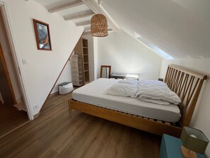 Una camera da letto con un letto di legno, un lucernario, un armadio e una lampada a sospensione.