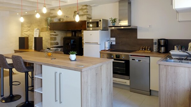 A modern kitchen with a central island, built-in appliances, and pendant lighting. - Charming house for 4 near town center (Sarzeau)