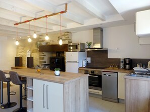 A modern kitchen with a central island, built-in appliances, and pendant lighting. - Charming house for 4 near town center (Sarzeau)