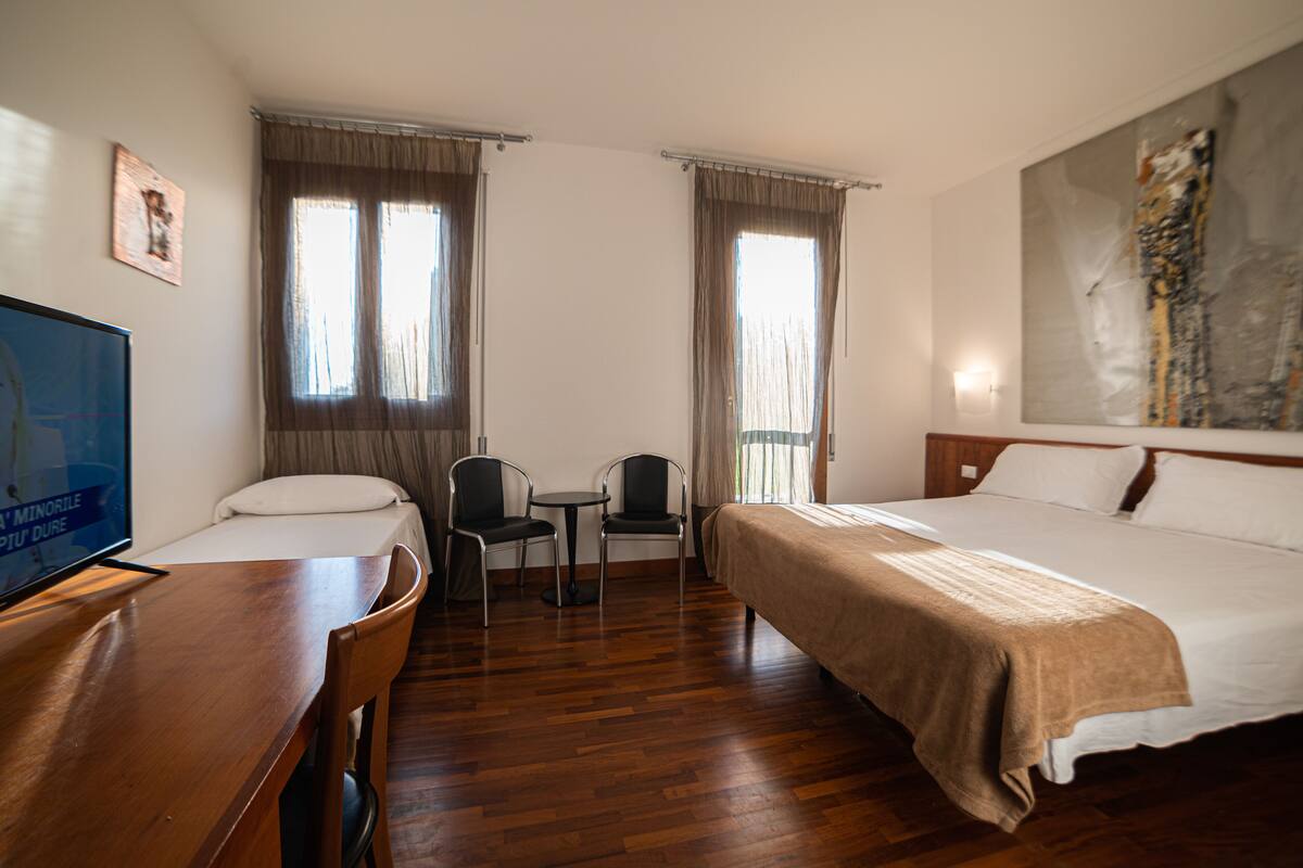 Ein Hotelzimmer mit einem Bett, einem Schreibtisch mit Stuhl, einem kleinen Tisch und einem Fernseher.