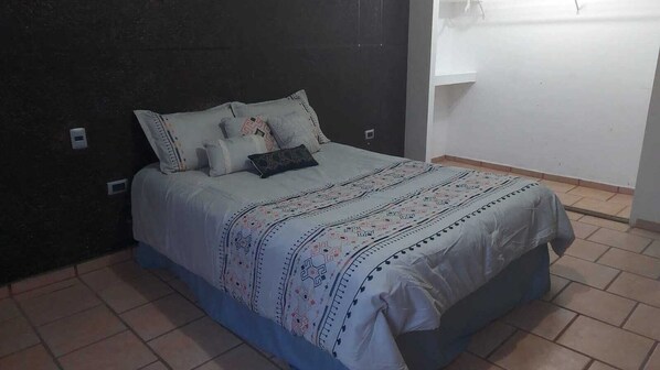 Un dormitorio con una cama, almohadas y una mesita de noche.