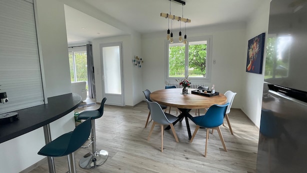 Una cucina moderna con un tavolo rotondo in legno, sedie blu e un frigorifero in acciaio inox.