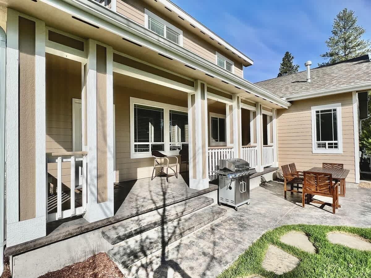 A two-story house with a covered porch, outdoor seating, and a grill.