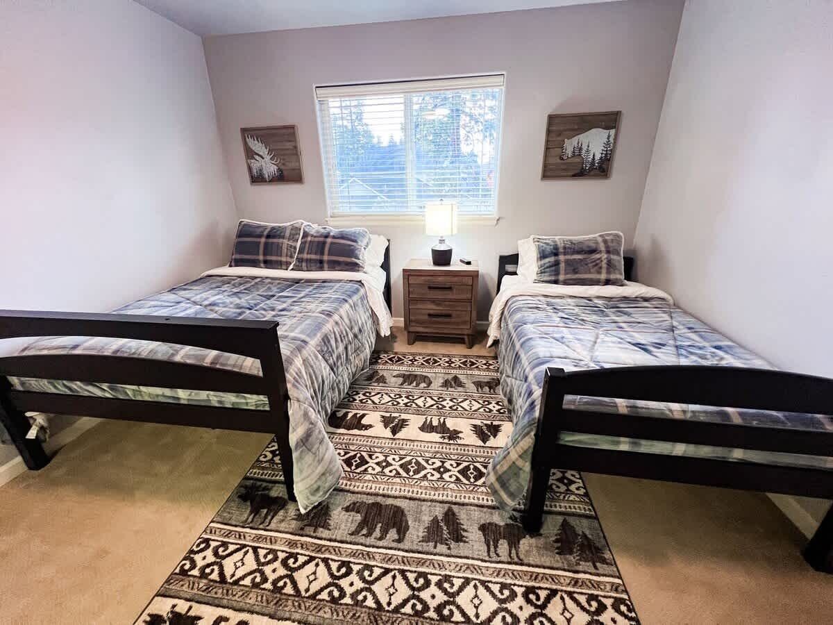 A bedroom with two beds, a window, and a rug with animal patterns.