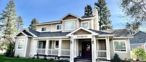 A two-story house with a front porch, a chimney, and a well-maintained lawn.