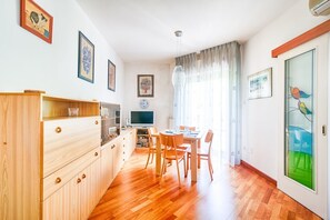 Eine moderne Küche mit Holzausstattung, ein Essbereich mit Tisch und Stühlen sowie ein Fernseher.