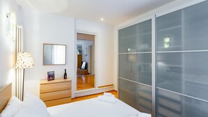 A hotel room with a bed, a dresser, a lamp, a mirror, and a sliding glass door. - GuestHost - Ponte Solferino Bright & Cozy APT (Pisa)
