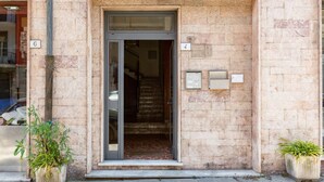 A building entrance with a glass door, numbered 4, and a stone facade. - GuestHost - Ponte Solferino Bright & Cozy APT (Pisa)