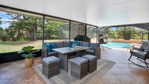 A covered outdoor patio with a dining set, seating area, and a view of a swimming pool. - Casa Boca - Perfect Florida Getaway with Large Heated Saltwater Pool (Boca Raton)