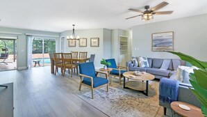 A spacious living room with a dining area, a ceiling fan, and a large window. - Casa Boca - Perfect Florida Getaway with Large Heated Saltwater Pool (Boca Raton)