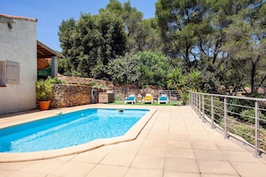 A swimming pool with a stone wall and a metal railing.