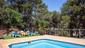 Une piscine avec des chaises longues et un mur en pierre.
