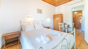 Ein Schlafzimmer mit Bett, Nachttisch, Kleiderschrank und einem kleinen Esstisch mit Stühlen.
