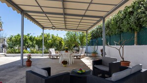 An outdoor patio with wicker furniture, a table, and potted plants.