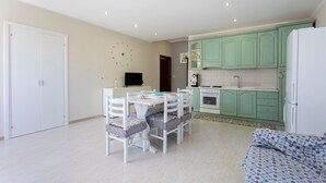 A compact living space with a dining area, kitchenette, and a sofa.