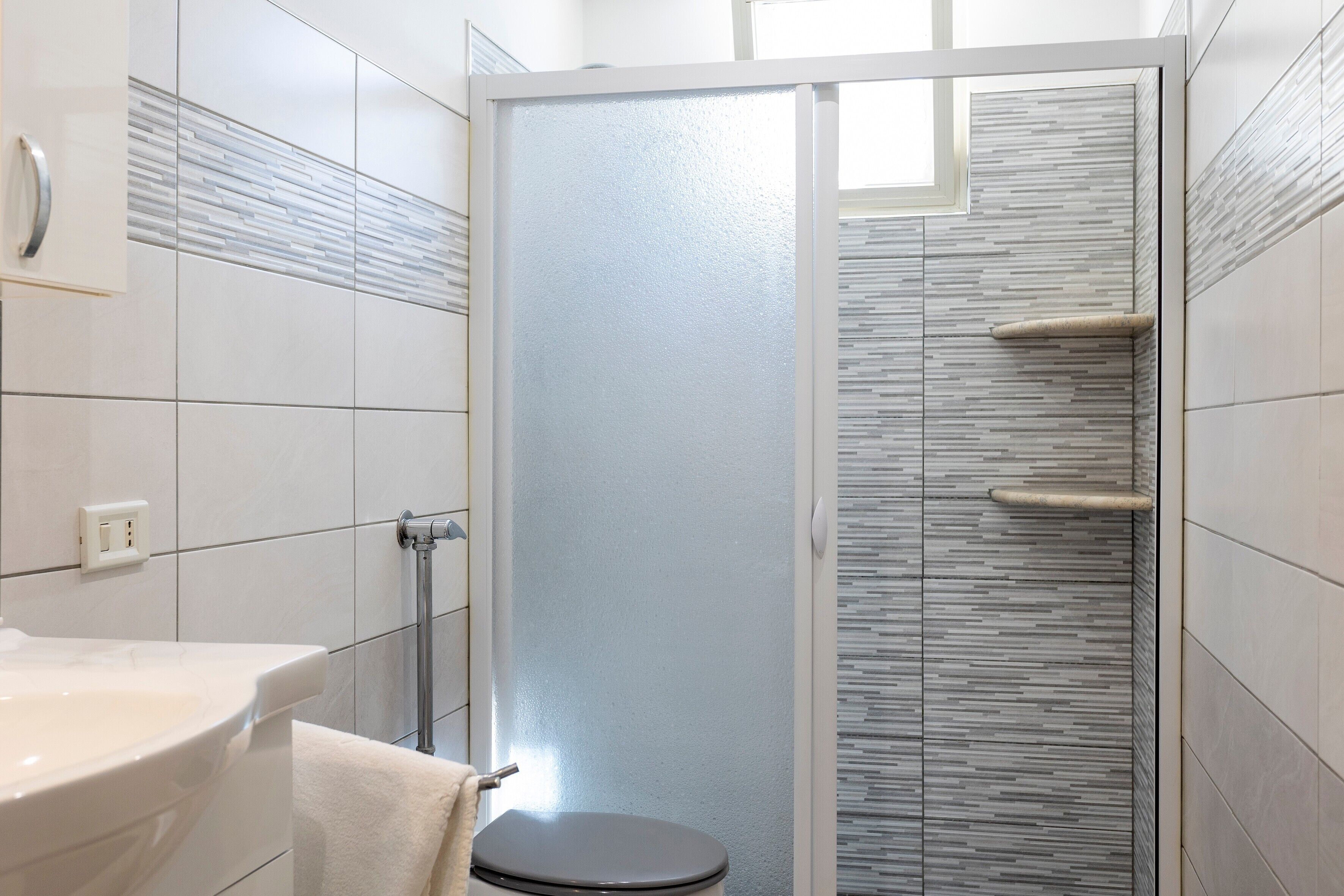 A bathroom with a toilet, sink, and shower area.