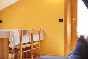 A room with a dining table, chairs, and a wooden door.