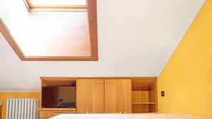 A bedroom with a skylight, wooden furniture, and a television. - 'Chalet Letizia Apartment Bilo' with Mountain View, Balcony & Wi-Fi (Livigno)