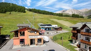 A mountain resort with a rental building, a ski lift, and a view of the surrounding hills. - 'Chalet Letizia Apartments Trilo' with Mountain View, Balconies & Wi-Fi (Livigno)