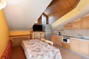 A compact kitchen with wooden cabinets, a refrigerator, a microwave, and a sink.