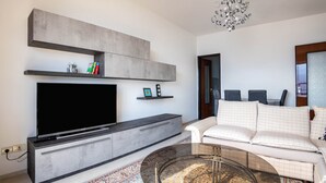 A modern living room with a flat-screen TV, a sofa, a coffee table, and a chandelier. - Apartment 'with Stunning Views' and Balcony (Tremosine)