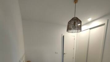 Een slaapkamer met een bed, nachtkastje, hanglamp en een kledingkast.