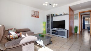 En moderne stue med sofa, sofabord, fjernsyn og multimøbel.