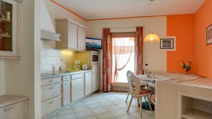 A kitchen with white cabinets, a coffee maker, and a television.