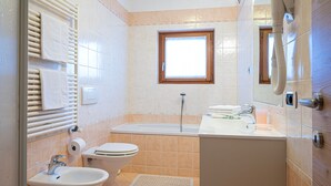 A bathroom with a bathtub, toilet, sink, and a window.