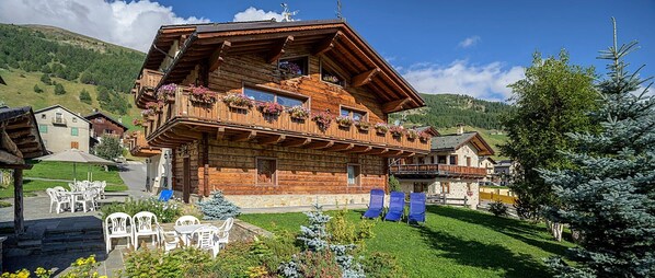Un chalet en bois doté de balcons, d’un espace extérieur aménagé et surplombant un paysage montagneux.