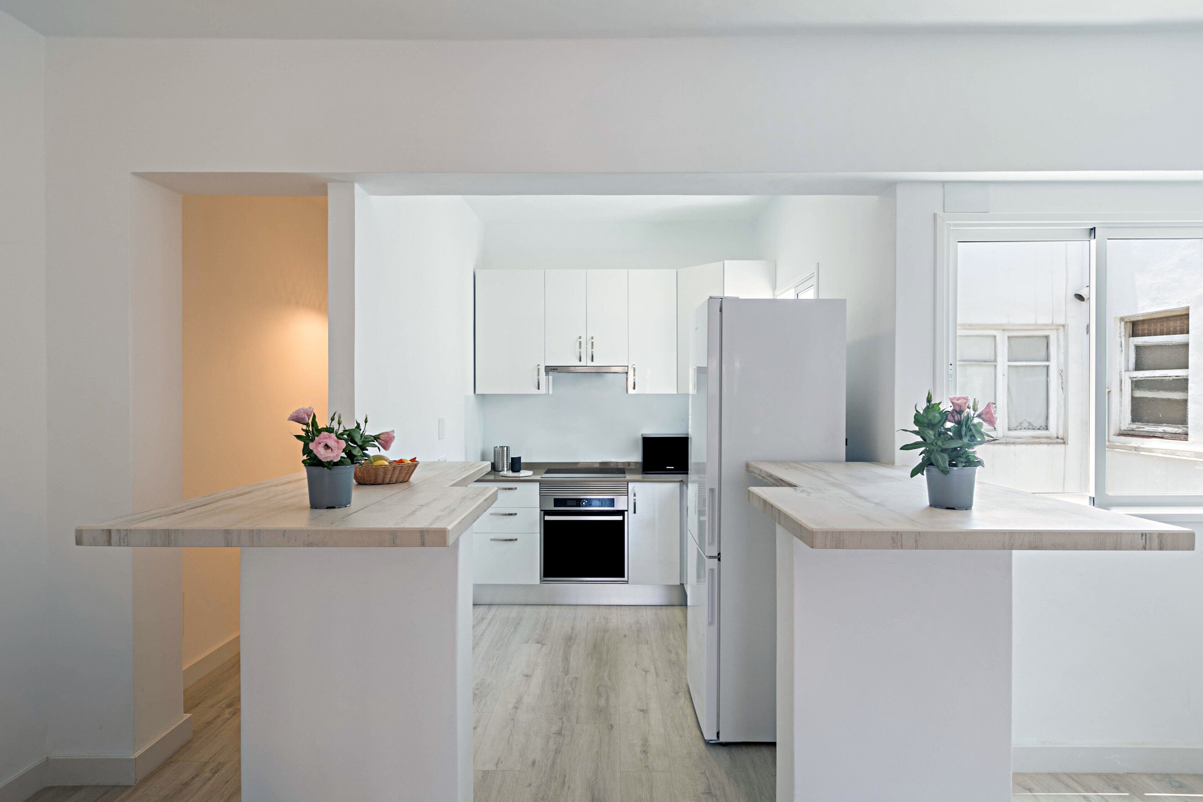 A modern kitchen with white cabinets, a built-in oven, and a refrigerator.
