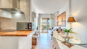 A modern kitchen with a microwave, a glass dining table, and a sofa. - ‘Romana Playa’ Apartment with Pool, Wi-Fi & Air Conditioning (Marbella)