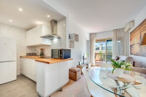 A modern kitchen with white cabinets, a built-in microwave, and a stainless steel range hood.