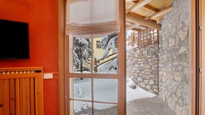 Una habitación con un ventanal grande, una puerta de madera y una pared de piedra en el exterior.