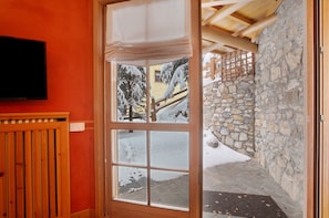 Una stanza con un'ampia finestra, una porta in legno e un muro di pietra all'esterno.