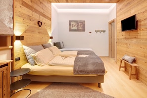 A bedroom with a bed, bedside tables, a TV, and a wooden wall.