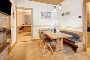 A wooden dining table with benches, a television, and a painting on the wall.