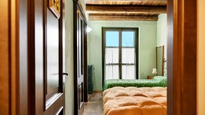 A narrow hallway leading to a bedroom with a bed, a window, and a mirror.