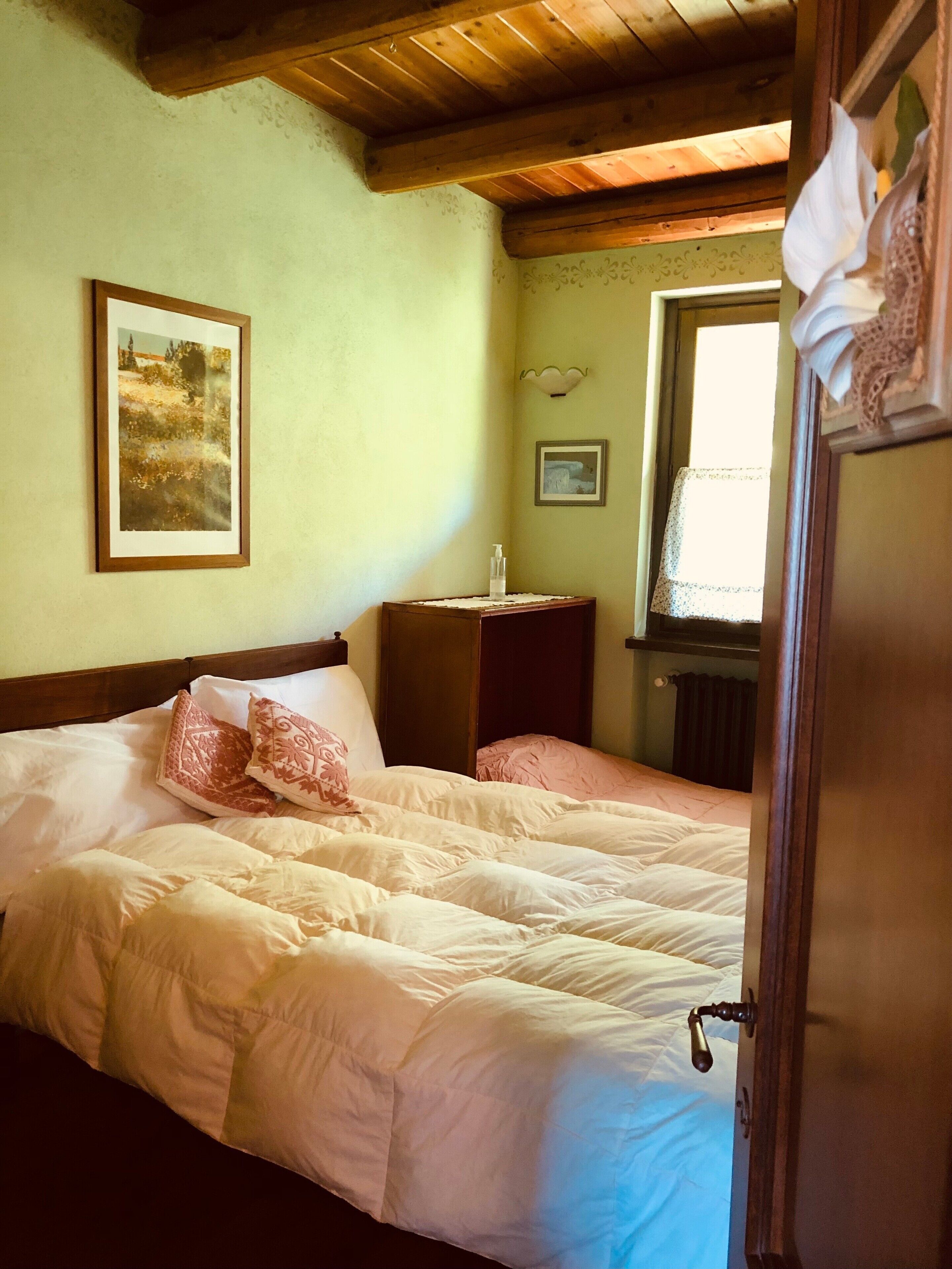 Una camera da letto con un letto, un comodino, una finestra e una porta.