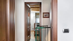 A hallway with wooden doors, a green railing, and a radiator.