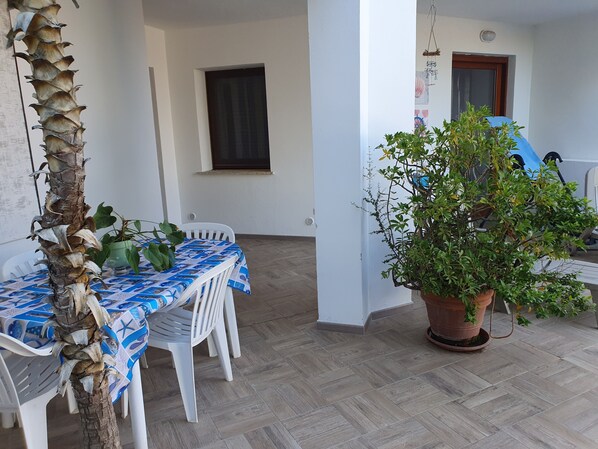 A patio with a table and chairs, a potted plant, and a window.