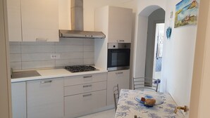 A compact kitchen with a gas stove, oven, and white cabinets.